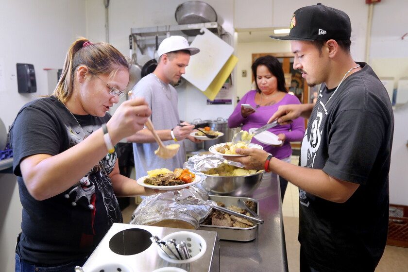 Volunteers and community members serving plates of food together at a holiday meal service